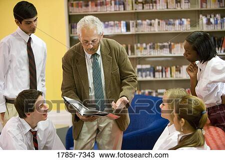 Teenage boy and girl students wearing uniforms with their teacher in a library View Large Photo Image Stock Image - Teenage boy and girl students wearing uniforms with their teacher in a library. Fotosearch