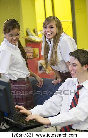 Teenage boy in school uniform using computer while girls watch View Large Photo Image Stock Image - Teenage boy in school uniform using computer while girls watch. Fotosearch