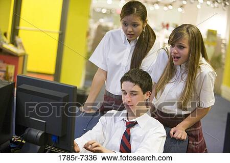 Teenage boy in school uniform using computer while girls watch View Large Photo Image Stock Photograph - Teenage boy in school uniform using computer while girls watch. Fotosearch
