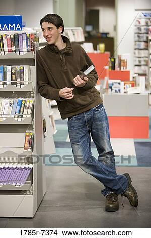 Teenage boy leaning on bookshelf in the library View Large Photo Image Picture - Teenage boy leaning on bookshelf in the library. Fotosearch