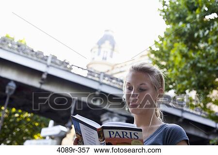 Stock Photo - Teenage girl reading a guidebook, Paris, Ile-de-France, France. Fotosearch