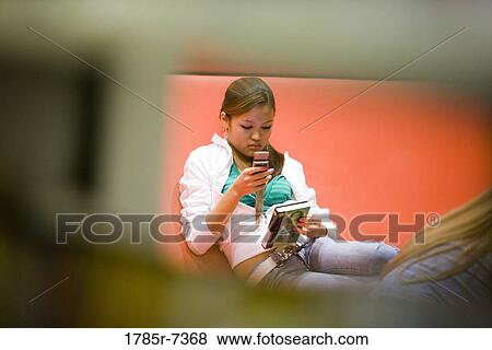 Teenage girl sitting with mobile phone and book View Large Photo Image Stock Photo - Teenage girl sitting with mobile phone and book. Fotosearch