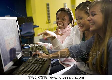 Teenage girlfriends cheerfully working at a computer together View Large Photo Image Stock Photo - Teenage girlfriends cheerfully working at a computer together. Fotosearch