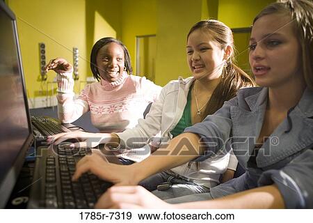 Teenage girlfriends cheerfully working at a computer together View Large Photo Image Stock Photo - Teenage girlfriends cheerfully working at a computer together. Fotosearch
