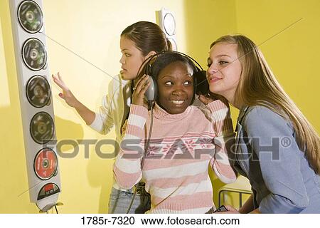 Teenage girlfriends listening to music on a headset together View Large Photo Image Stock Image - Teenage girlfriends listening to music on a headset together. Fotosearch