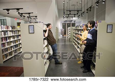 Three teenage boys conversing in a library View Large Photo Image Stock Image - Three teenage boys conversing in a library. Fotosearch