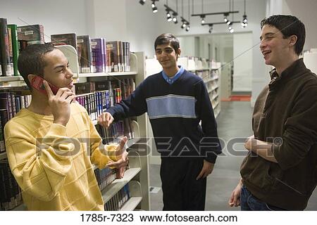 Three teenage boys conversing in a library View Large Photo Image Stock Image - Three teenage boys conversing in a library. Fotosearch