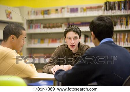 Stock Photo - Three teenage boys conversing in library. Fotosearch