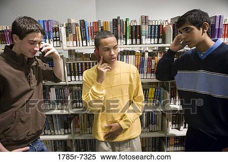 Three teenage boys talking on cell phones in a library View Large Photo Image Stock Photography - Three teenage boys talking on cell phones in a library. Fotosearch