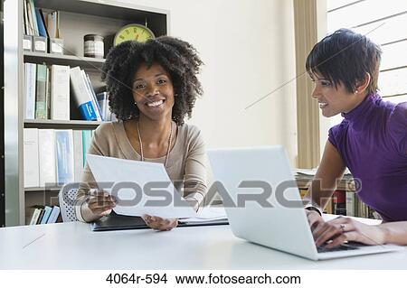 Picture - Two businesswomen working on project in office. Fotosearch