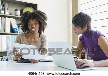 Two businesswomen working on project in office View Large Photo Image Stock Image - Two businesswomen working on project in office. Fotosearch