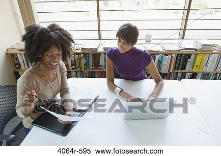 Stock Photography - Two businesswomen working on project in office. Fotosearch