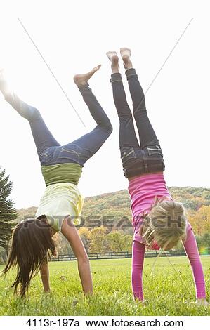 Two girls doing handstand in field View Large Photo Image Stock Image - Two girls doing handstand in field. Fotosearch