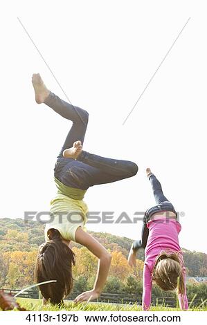 Two girls doing handstand in field View Large Photo Image Stock Image - Two girls doing handstand in field. Fotosearch