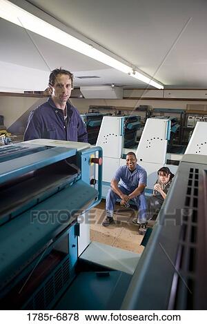 Two men and a woman in coveralls in front of a printing machine View Large Photo Image Stock Photo - Two men and a woman in coveralls in front of a printing machine. Fotosearch