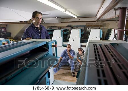 Two men and a woman in coveralls in front of a printing machine View Large Photo Image Stock Photo - Two men and a woman in coveralls in front of a printing machine. Fotosearch