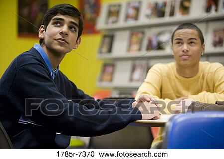 Two teenage boys in sitting at a table in the library View Large Photo Image Stock Image - Two teenage boys in sitting at a table in the library. Fotosearch