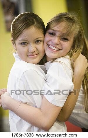 Two teenage girlfriends hugging one another View Large Photo Image Stock Image - Two teenage girlfriends hugging one another. Fotosearch