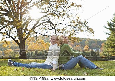 Stock Image - Two women sitting on field. Fotosearch