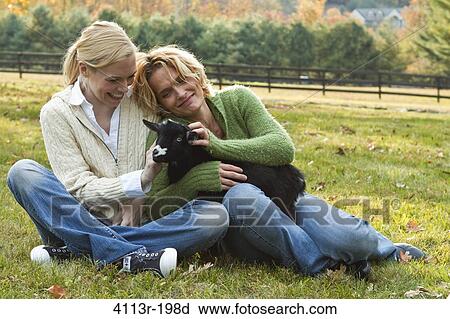 Two women with black lamb sitting on field View Large Photo Image Stock Image - Two women with black lamb sitting on field. Fotosearch