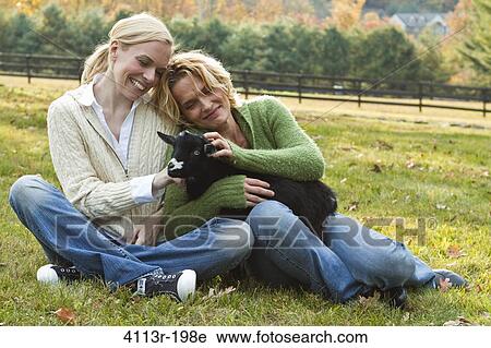 Two women with black lamb sitting on field View Large Photo Image Stock Image - Two women with black lamb sitting on field. Fotosearch