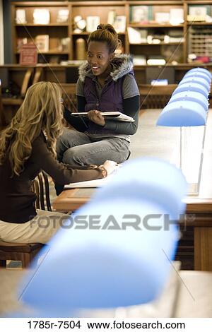 Two young women sitting in the reading room of a library View Large Photo Image Picture - Two young women sitting in the reading room of a library. Fotosearch