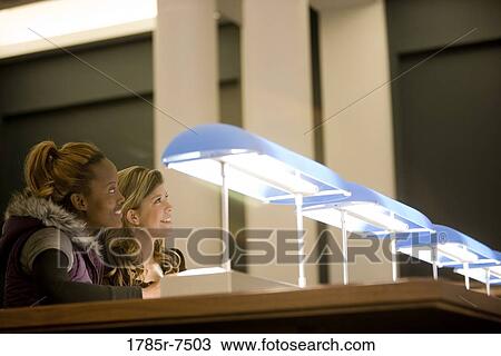 Two young women sitting in the reading room of a library View Large Photo Image Stock Image - Two young women sitting in the reading room of a library. Fotosearch