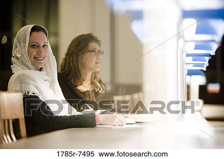 Stock Photography - Two young women sitting in the reading room of a library. Fotosearch