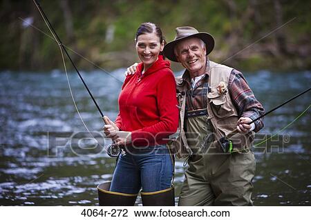 Stock Image - USA, Washington, Vancouver, Portrait of smiling couple fishing in river. Fotosearch