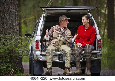 Stock Image - USA, Washington, Vancouver, Smiling couple sitting in back of car after fishing. Fotosearch