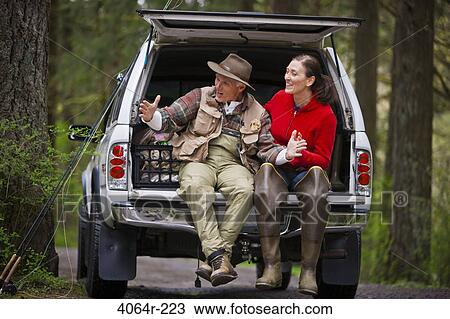 Stock Image - USA, Washington, Vancouver, Smiling couple sitting in back of car after fishing. Fotosearch