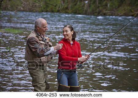 Stock Image - USA, Washington, Vancouver, Smiling couple fishing in river. Fotosearch