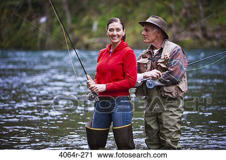 Stock Image - USA, Washington, Vancouver, Smiling couple fishing in river. Fotosearch