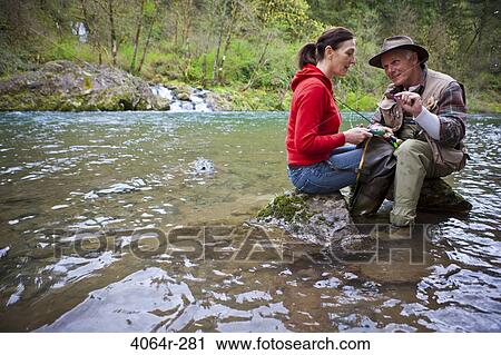 Stock Image - USA, Washington, Vancouver, Smiling couple fishing in river. Fotosearch