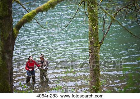 Stock Image - USA, Washington, Vancouver, Smiling couple fishing in river. Fotosearch