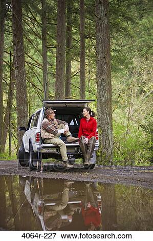 Stock Photo - USA, Washington, Vancouver, Smiling couple sitting in back of car after fishing. Fotosearch