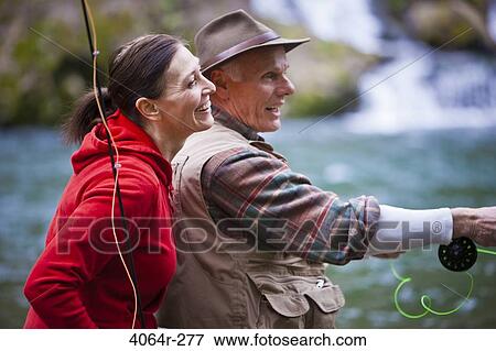 Stock Photo - USA, Washington, Vancouver, Smiling couple fishing in river. Fotosearch