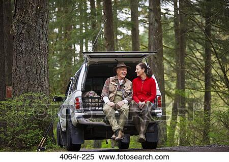Stock Photography - USA, Washington, Vancouver, Smiling couple sitting in back of car after fishing. Fotosearch