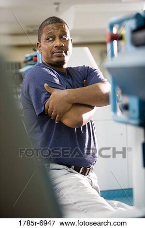 View of a blue-collar man standing in front of some some machinery View Large Photo Image Stock Photo - View of a blue-collar man standing in front of some some machinery. Fotosearch