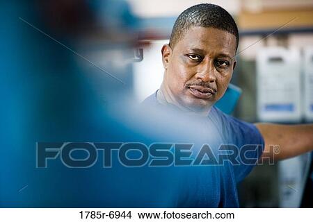 View of a blue-collar man standing behind some machinery View Large Photo Image Picture - View of a blue-collar man standing behind some machinery. Fotosearch