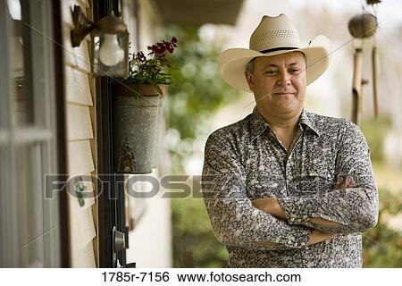 View of a contemplative mature man wearing cowboy hat in front of house View Large Photo Image Stock Photograph - View of a contemplative mature man wearing cowboy hat in front of house. Fotosearch
