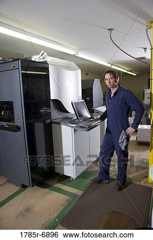 View of a man in coveralls operating a machine by using a computer View Large Photo Image Stock Photograph - View of a man in coveralls operating a machine by using a computer. Fotosearch