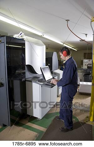 View of a man in coveralls operating a machine by using a computer View Large Photo Image Stock Photography - View of a man in coveralls operating a machine by using a computer. Fotosearch