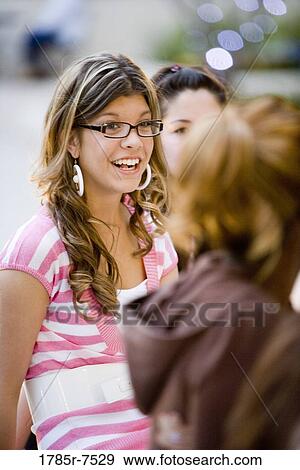 Stock Photo - View of a smiling young woman with her friends. Fotosearch
