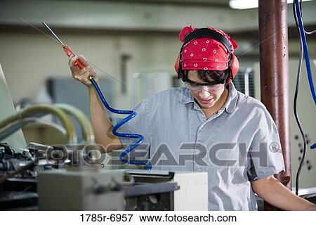 View of a woman in coveralls and safety gear operating some machinery View Large Photo Image Stock Photo - View of a woman in coveralls and safety gear operating some machinery. Fotosearch
