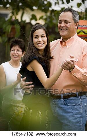 View of mature man dancing with his daughter while his wife cheers in the background View Large Photo Image Stock Image - View of mature man dancing with his daughter while his wife cheers in the background. Fotosearch