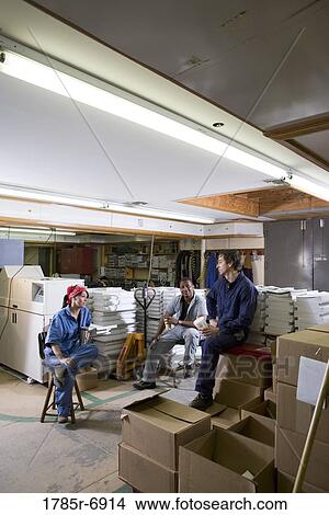 View of two men and a woman enjoying a coffee break while working in a warehouse View Large Photo Image Picture - View of two men and a woman enjoying a coffee break while working in a warehouse. Fotosearch