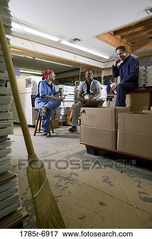 View of two men and a woman enjoying a coffee break while working in a warehouse View Large Photo Image Stock Photo - View of two men and a woman enjoying a coffee break while working in a warehouse. Fotosearch