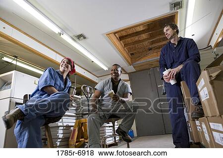 View of two men and a woman enjoying a coffee break while working in a warehouse View Large Photo Image Stock Photo - View of two men and a woman enjoying a coffee break while working in a warehouse. Fotosearch