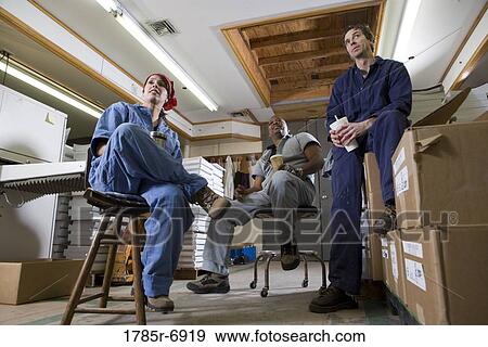 View of two men and a woman enjoying a coffee break while working in a warehouse View Large Photo Image Stock Photo - View of two men and a woman enjoying a coffee break while working in a warehouse. Fotosearch